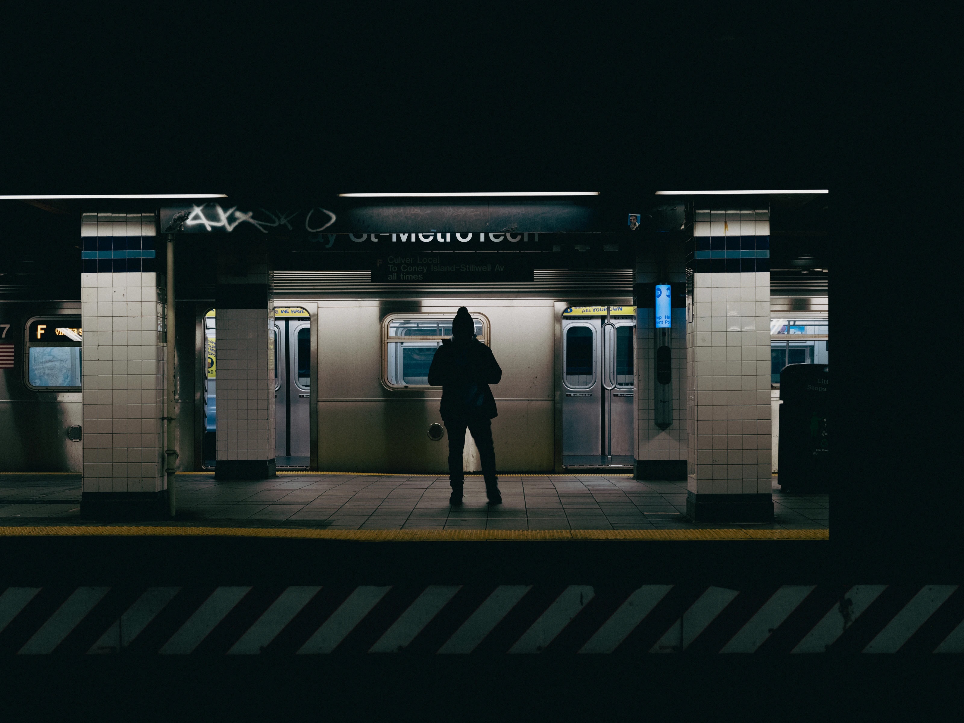 Silhouette of a person on a subway platform in front of a train, New York