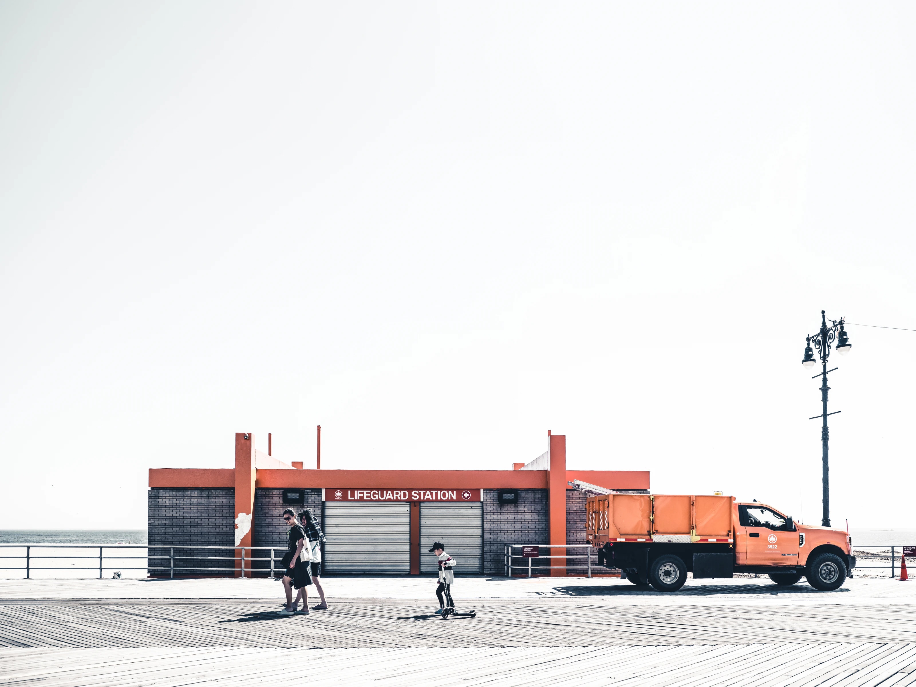 Lifeguard station on the Coney Island boardwalk with passers-by and an orange truck, New York